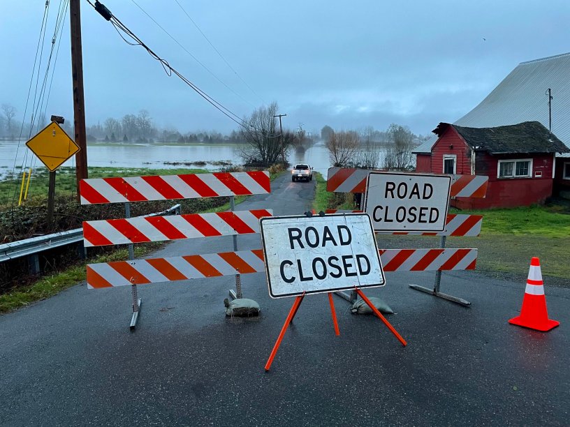 A closed sign in front of a flooded roadway