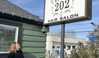 Woman standing outside looks up toward her business' sign