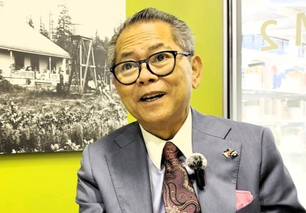 Man talking in a room with a black and white picture behind him