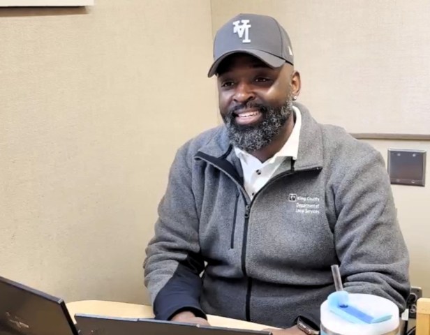 Man smiling while sitting behind a laptop in a room