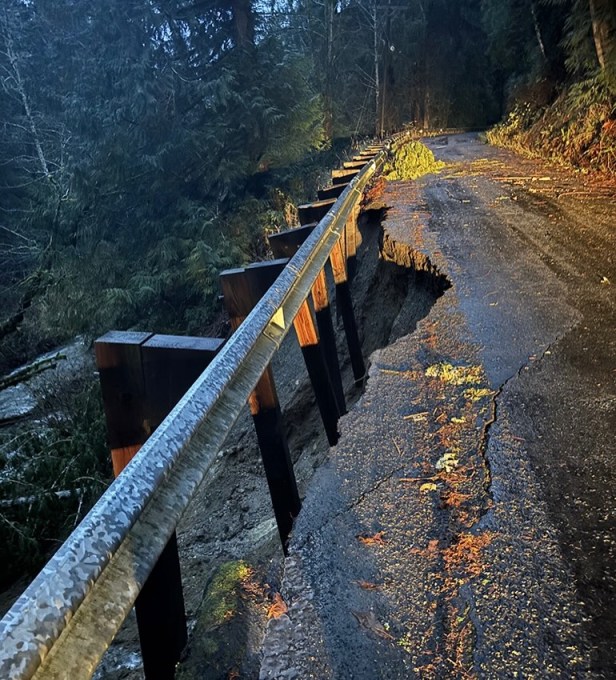 A portion of a roadway located in a forested area that was damaged by flooding.